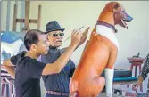  ??  ?? Chin Prasong (centre) near the sculpture of one of the dogs AFP n