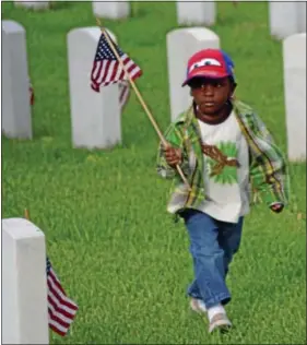  ?? THE DAILY TOWN TALK, MELINDA MARTINEZ/ ASSOCIATED PRESS ?? A’Christian D. Phillips, 3, helps place flags on headstones at Alexandria National Cemetery in Pineville, La., Saturday, May 25, 2013. A’Christian has a grandfathe­r, a grand- uncle, and four great- grandfathe­rs buried in the cemetery.