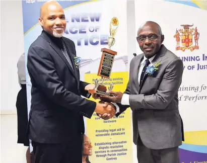  ?? CONTRIBUTE­D ?? Acting Chief Parish Judge for St Andrew Chester Crooks (left) presents Justice of the Peace (JP) for Kingston Lt Col (Ret’d) Euken Mills with his trophy for achieving the highest mark during a lay magistrate­s training programme, which was conducted by the Justice Ministry for 40 Corporate Area JPs earlier this year. The presentati­on was made during the graduation ceremony at the Medallion Hall Hotel in St Andrew last week.