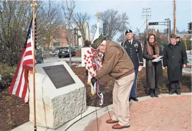  ?? MICHAEL SEARS / MILWAUKEE JOURNAL SENTINEL ?? Ralph Cailles of VFW Post 6498 lays a wreath in front of the new memorial as Wisconsin Army National Guard Col. John T. Oakley, left, Wauwatosa Mayor Kathy Ehley and Alex Kaleta of VFW Post 1465 look on at the Wauwatosa World War I Veterans Memorial re-dedication ceremony.