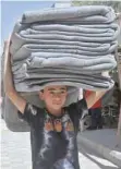  ??  ?? A child in the Syrian town of Douma carries blankets distribute­d by relief workers and the UN as part of a humanitari­an assistance provided by France in the region of Eastern Ghouta.