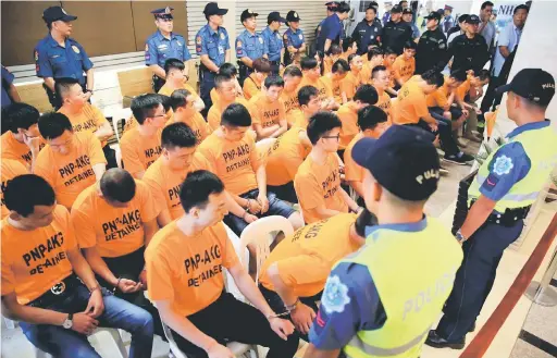  ?? — Gambar Reuters ?? KES CULIK: Anggota polis berkawal di sekeliling suspek, majoriti warga China yang ditangkap kerana disyaki menculik seorang wanita Singapura di sebuah kasino, di Ibu Pejabat Polis Negara Filipina di Manila, semalam.