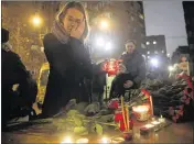  ?? PAVEL GOLOVKIN / AP ?? A woman lights a candle at the Alexandrov Ensemble building in Moscow on Sunday after a plane carrying 64 members of the group crashed.