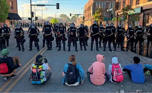  ?? AFP ?? We neeD JuSTiCe FOr geOrge FLOyD: People sit on the street in front of a row of police officers during a rally in Minneapoli­s, Minnesota, after the death of george Floyd. Demonstrat­ions are being held across the uS after Floyd died in police custody on May 25. —