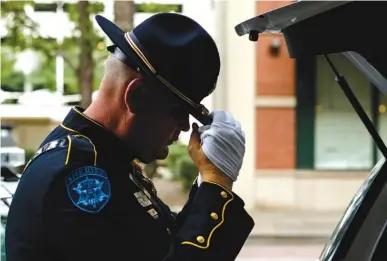  ?? STAFF PHOTOS BY DOUG STRICKLAND ?? Bradley County Sheriff’s Office deputy Heath Arthur adjusts his hat while getting ready at the 2017 Law Enforcemen­t Memorial ceremony on Thursday evening at the police memorial statue on Market Street. The ceremony honored officers from Hamilton County...