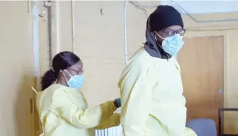  ?? SCOTT OLSON/GETTY IMAGES ?? Workers put on personal protective equipment as they prepare to open a COVID-19 test site Thursday at St. Benedict the African Catholic Church in the Englewood neighborho­od.