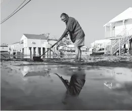  ?? JOHN LOCHER/AP ?? Cindy Rojas cleans mud, debris and floodwater­s from her driveway Sunday in Lafitte, a town of 2,000 people in Jefferson Parish, La. Hurricane Ida made landfall a week ago.