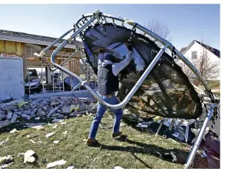  ?? BILL LACKEY / STAFF ?? Jake Martin flips a broken trampoline onto a garbage pile as he helps his brother, Andy, clean up his yard on Thursday. Andy’s house was one of several around Mitchell Road in Springfiel­d Twp. that were damaged or destroyed by Wednesday morning’s EF2 tornado.