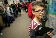  ?? NWA Democrat-Gazette/DAVID GOTTSCHALK ?? Aiden Thomas, a sixth-grade student at Holt Middle School, clutches his Chromebook on Wednesday in the hallway as he stands with students before transferri­ng to his next class.