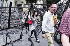  ??  ?? TAIPEIO: Government employees walk between barricades erected outside the parliament during an anti-pension reform demonstrat­ion. —AFP