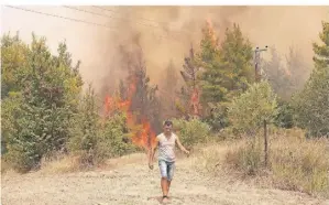  ?? FOTO: PETROS KARADJIAS/AP/DPA ?? Ein Mann vor einem Waldbrand im Dorf Avgaria auf der Insel Euböa. Sie wurde 2021 besonders schlimm getroffen.