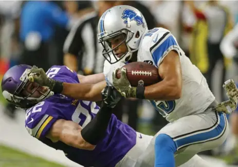  ?? BRUCE KLUCKHOHN/USA TODAY SPORTS ?? After the Lions forced OT with a late field goal, receiver Golden Tate fended off Vikings safety Harrison Smith on the way to the end zone to win it.