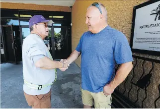  ?? JOHN MAHONEY ?? Mike Delisle Jr., right, greets Mouchie Goodleaf outside the post office in Kahnawake. Delisle, a former grand chief, is running for a seat on council this year.