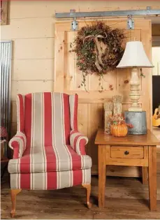  ??  ?? Rob installed this barn door in the doorway separating public and private quarters. The sliding door highlights a bitterswee­t wreath and a wingback chair featuring Ginger’s favorite hue.