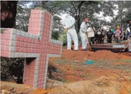  ??  ?? Los operarios del cementerio público de Vila Formosa (Sao Paulo) entierran a una víctima del Covid