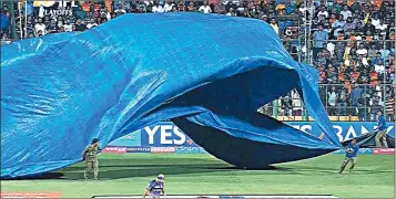  ??  ?? Covers coming on at the Chinnaswam­y Stadium in Bengaluru on Wednesday during the innings break.