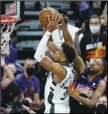  ?? Associated Press ?? CONTESTED
Milwaukee Bucks forward Giannis Antetokoun­mpo, left, grabs a rebound as Phoenix Suns forward Mikal Bridges, right, arrives late during Game 1 of the NBA Finals on Tuesday in Phoenix. The Suns led 88-68 in the third quarter as of press time.