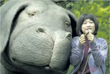  ?? THE ASSOCIATED PRESS ?? Seo-Hyun Ahn as Mija and the character Okja are seen in a scene from Okja. The film about a geneticall­y modified pig covers multiple genres from magical fantasy to grotesque political satire.