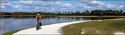  ?? The Washington Post/SELINA KOK ?? A cyclist tours the 1.75-mile track around Sunset Lake at Babcock Ranch in southwest Florida. A growing web of bike and walking trails is spreading around the new, environmen­tally friendly community.