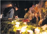  ??  ?? TEARS A woman kneels to place a candle outside synagogue