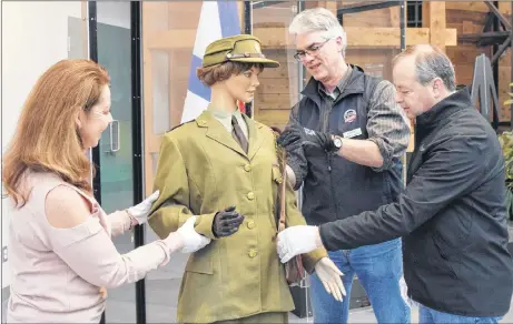  ?? ADAM MACINNIS/THE NEWS ?? Museum of Industry employees Denise Taylor and Andrew Phillips with help from David Avery set up a manikin wearing a uniform that would have been worn by a captain in the Canadian Women’s Army Corps during the Second World War.