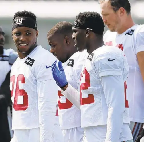  ?? AP ?? A day after injuring hamstring, Saquon Barkley (l.) takes it easy as Giants practice at Lions’ training facility Tuesday.