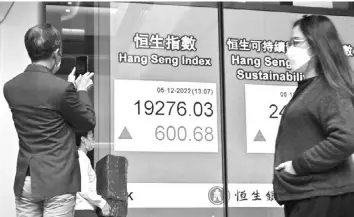  ?? AGENCE FRANCE PRESSE ?? Pedestrian­s pass an electronic board showing the numbers for the Hang Seng Index in Hong Kong on December 5, 2022.