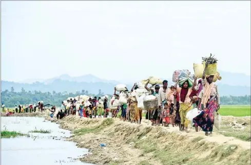  ?? MUNIR UZ ZAMAN/AFP ?? This file photo taken in 2017 shows Rohingya refugees walk near the no man’s land area between Bangladesh and Myanmar in the Palongkhal­i area next to Ukhia.