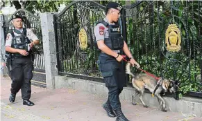  ?? — AP ?? Safety checks: Police officers leading a sniffer dog around the General Election Commission office one day after the election in Jakarta.