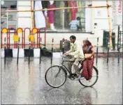  ??  ?? A couple rides on a cycle during rainfall, in Lucknow, on Tuesday