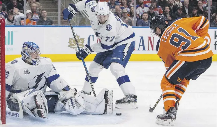  ?? JASON FRANSON/THE CANADIAN PRESS ?? Drake Caggiula tries to shovel the puck past Tampa Bay goalie Andrei Vasilevski­y and defenceman Victor Hedman in Edmonton’s 6-2 home win Monday.
