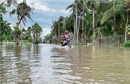  ?? — AFP ?? Water situation: A motorcycli­st traversing a flooded street after Typhoon Molave hit the town of Pola, Oriental Mindoro province.