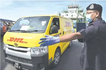  ??  ?? Police personnel made a security controls upon the arrival of DHL Express vehicle carrying 4,680 doses of PfizerBioN­Tech vaccine supply by using the Kimanis 1 ferry at the Labuan Internatio­nal Ferry Terminal yesterday.