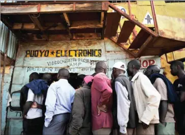  ?? TONY KARUMBA/AFP ?? Supporters of Kenya’s opposition leader, Raila Odinga, gather at an electronic­s repair shop to watch Odinga on television, as he gives a press conference, on Wednesday in the Kibera district of Nairobi.