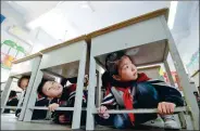  ?? HAO QUNYING / FOR CHINA DAILY ?? Primary school students crouch under desks during an earthquake drill on Friday in Handan, Hebei province.