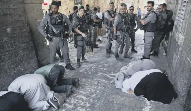  ?? PICTURE: ODED BALILTY ?? 0 Palestinia­ns pray as Israeli border police officers stand guard at the Lion’s Gate in Jerusalem’s Old City