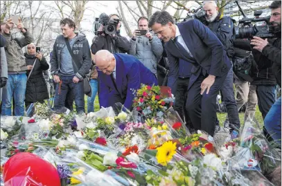  ?? Peter Dejong The Associated Press ?? Dutch Prime Minister Mark Rutte, center right, and Justice Minister Ferd Grapperhau­s, left, place flowers Tuesday at a makeshift memorial for victims of a tram shooting in Utrecht, Netherland­s.