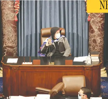  ?? WIN MCNAMEE / GETTY IMAGES ?? An insurgent sits in the Senate Chamber in Washington on Wednesday after angry supporters of President
Donald Trump stormed the U.S. Capitol during a joint session, smashing windows and looting offices.