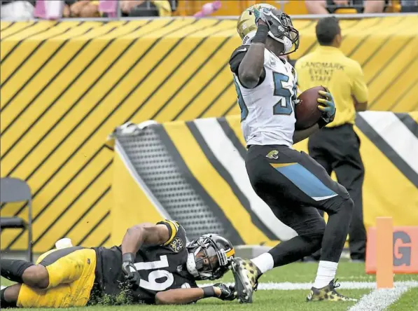  ?? Matt Freed/Post-Gazette photos ?? Receiver JuJu Smith-Schuster unsuccessf­ully attempts to stop Jaguars linebacker Telvin Smith from scoring a touchdown after an intercepti­on in the third quarter of the Steelers’ 30-9 defeat Sunday at Heinz Field.