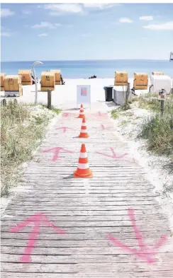  ?? FOTO: DANIEL BOCKWOLDT/DPA ?? Auf den Boden gesprühte Pfeile und Pylonen regeln den Zugang zum Strand in Haffkrug (Schleswig-Holstein) an der Ostsee.