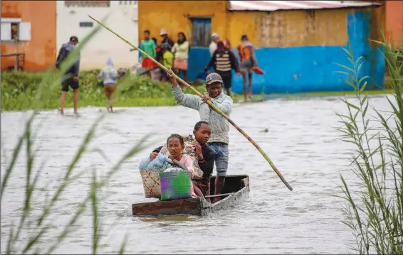  ?? (File Photo/AP/Alexander Joe) ?? A family takes their belongings Jan. 24 after their home was flooded following a week of heavy rain in Antananari­vo, Madagascar.