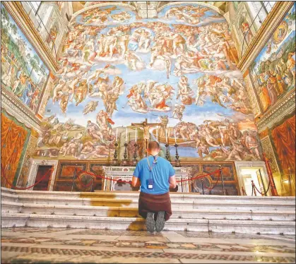  ?? (AP/Alessandra Tarantino) ?? A visitor kneels in front of the Last Judgement fresco by the Italian Renaissanc­e painter Michelange­lo inside the Sistine Chapel of the Vatican Museums on the occasion of the museum’s opening in Rome.