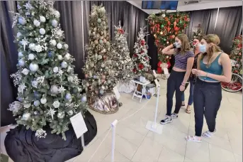  ?? Dan Watson/The Signal ?? Taylor Koebel, 12, center, and Riley Koebel, 16, of Newhall discuss the full-sized, decorated trees on display during the Boys & Girls Club Festival of Trees event held at Westfield Valencia Town Center in Valencia on Nov. 21, 2020.