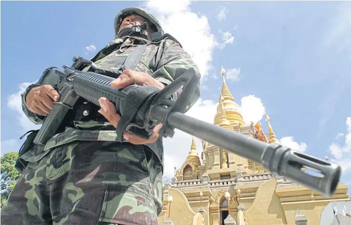  ??  ?? GUARDING THE FUTURE: An armed soldier stands in front of Wat Phra Maha Jedi in Betong district, Yala.