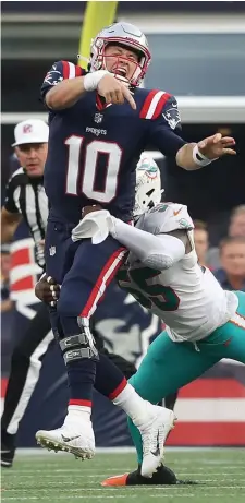  ?? NANCY LANE / HERALD STAFF FILE ?? STRONG FIN-ISH: Patriots quarterbac­k Mac Jones is hit by Dolphins outside linebacker Jerome Baker after getting off a pass during the third quarter at Gillette Stadium on Sunday.