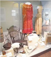  ?? [PHOTO BY NATE BILLINGS, THE OKLAHOMAN] ?? Women’s clothing, furniture and a butter churn typical of the time when the “Oklahoma!” musical is set occupy a display case at the Oklahoma History Center.