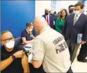  ?? Wilfredo Lee Associated Press ?? FLORIDA Gov. Ron DeSantis, right, watches as a man receives a COVID-19 shot in January 2021.