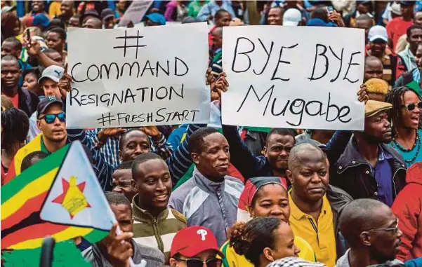  ??  ?? Orang ramai memegang sepanduk ketika melancarka­n satu bantahan menuntut peletakan jawatan Presiden Zimbabwe di Harare, semalam.