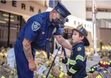  ??  ?? Bernalillo County Fire Department member Phillip Sanchez speaks with 7-year-old Santiago Garcia Urioste during a ceremony honoring first responders killed in the Sept. 11 attacks. Santiago’s mother, Erin Urioste, said they attended to pay their respects.