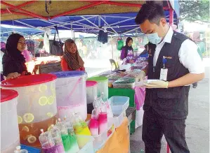  ??  ?? PEGAWAI Unit Kesihatan Persekitar­an PKK Beluran memeriksa gerai di Bazar Ramadan Pekan Beluran.